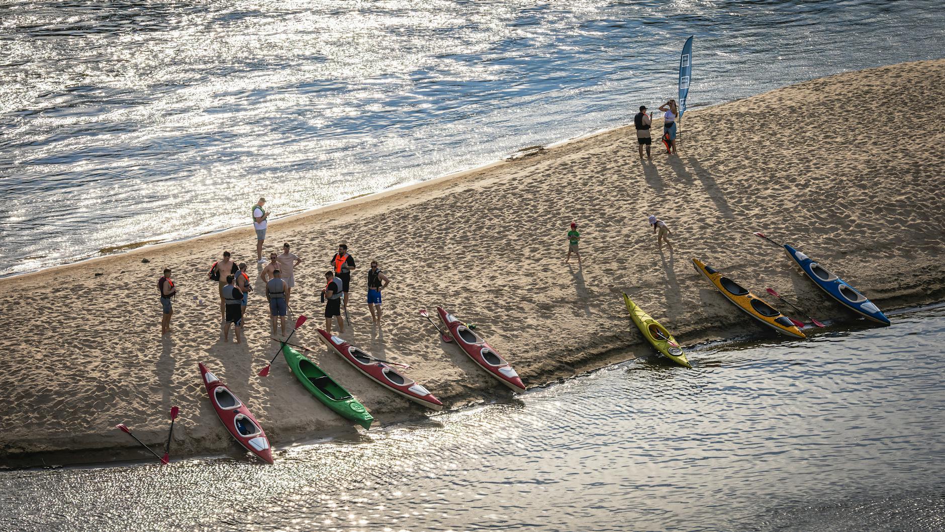 Kajakarze szykujący się do spływu na piaszczystej plaży w Warszawie