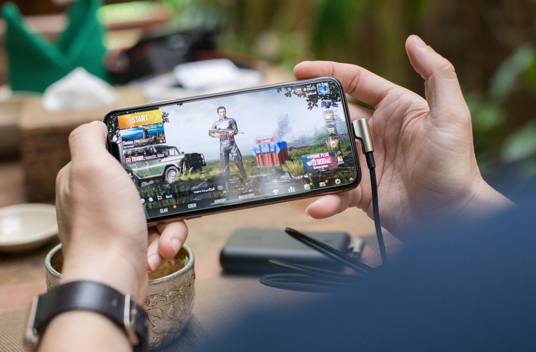 Osoba grająca w grę mobilną na smartfonie podłączonym do ładowarki