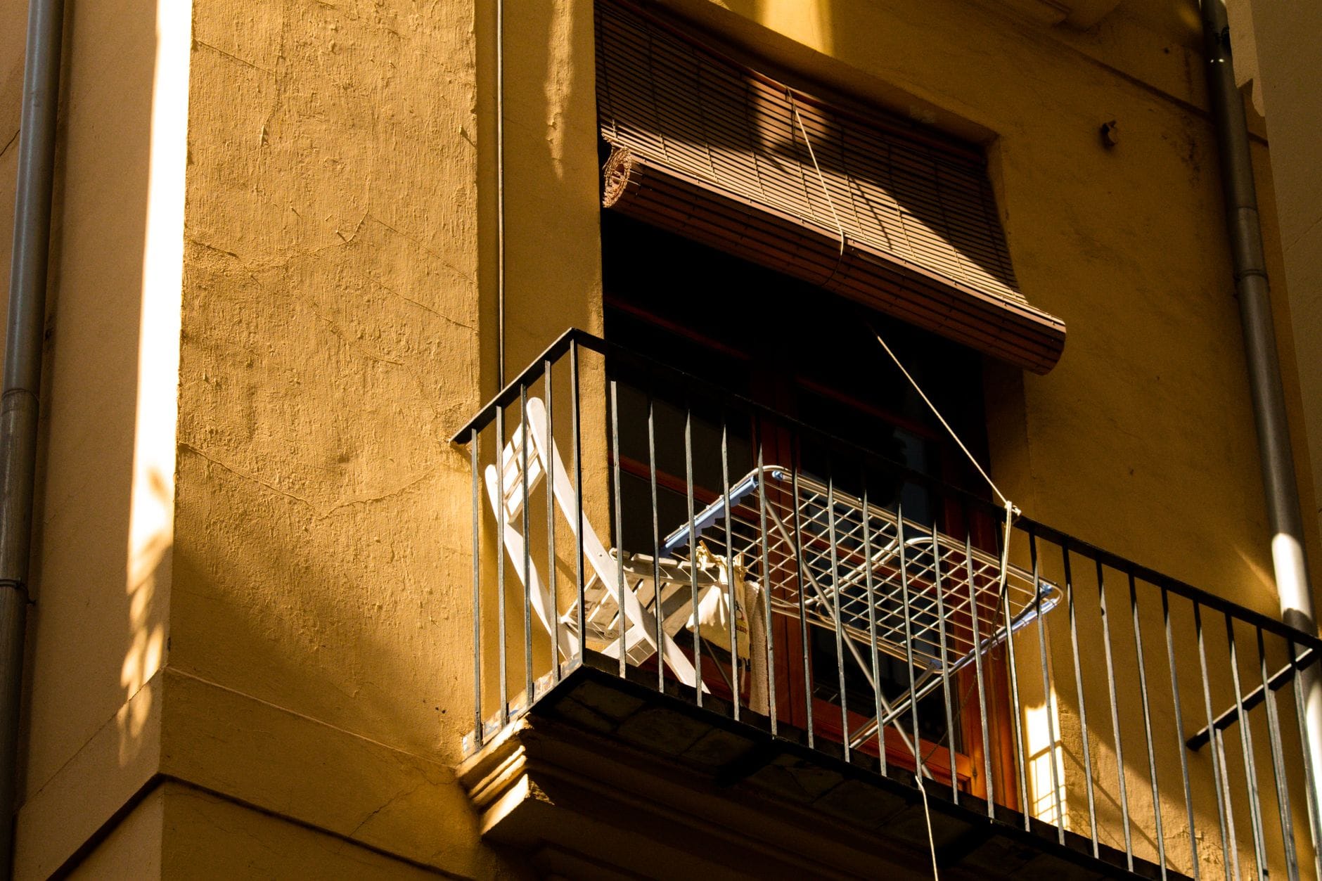 Mały balkon z krzesłem i suszarką na pranie w słonecznym mieście