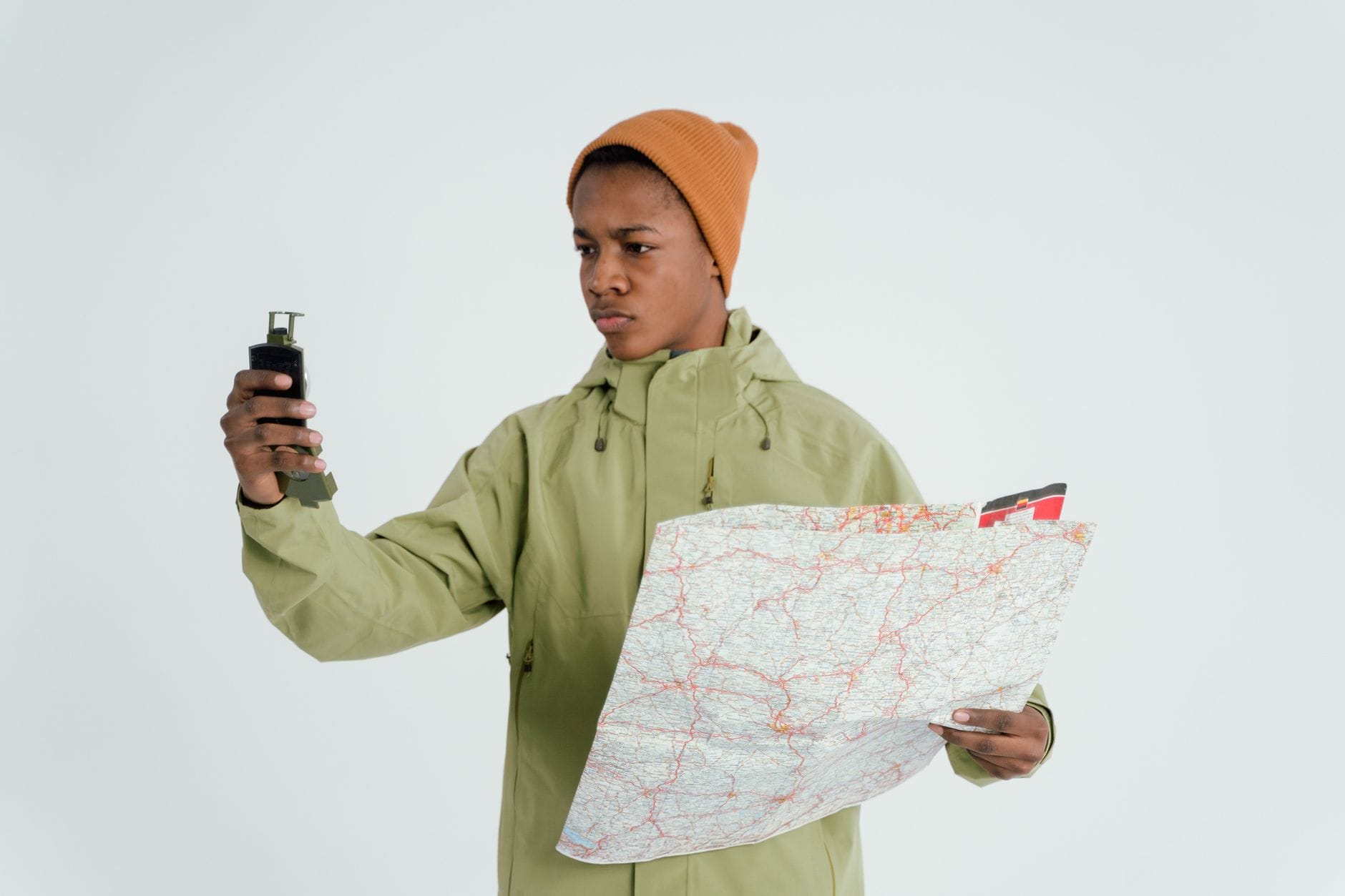 Młody mężczyzna w terenie sprawdza papierową mapę i urządzenie GPS