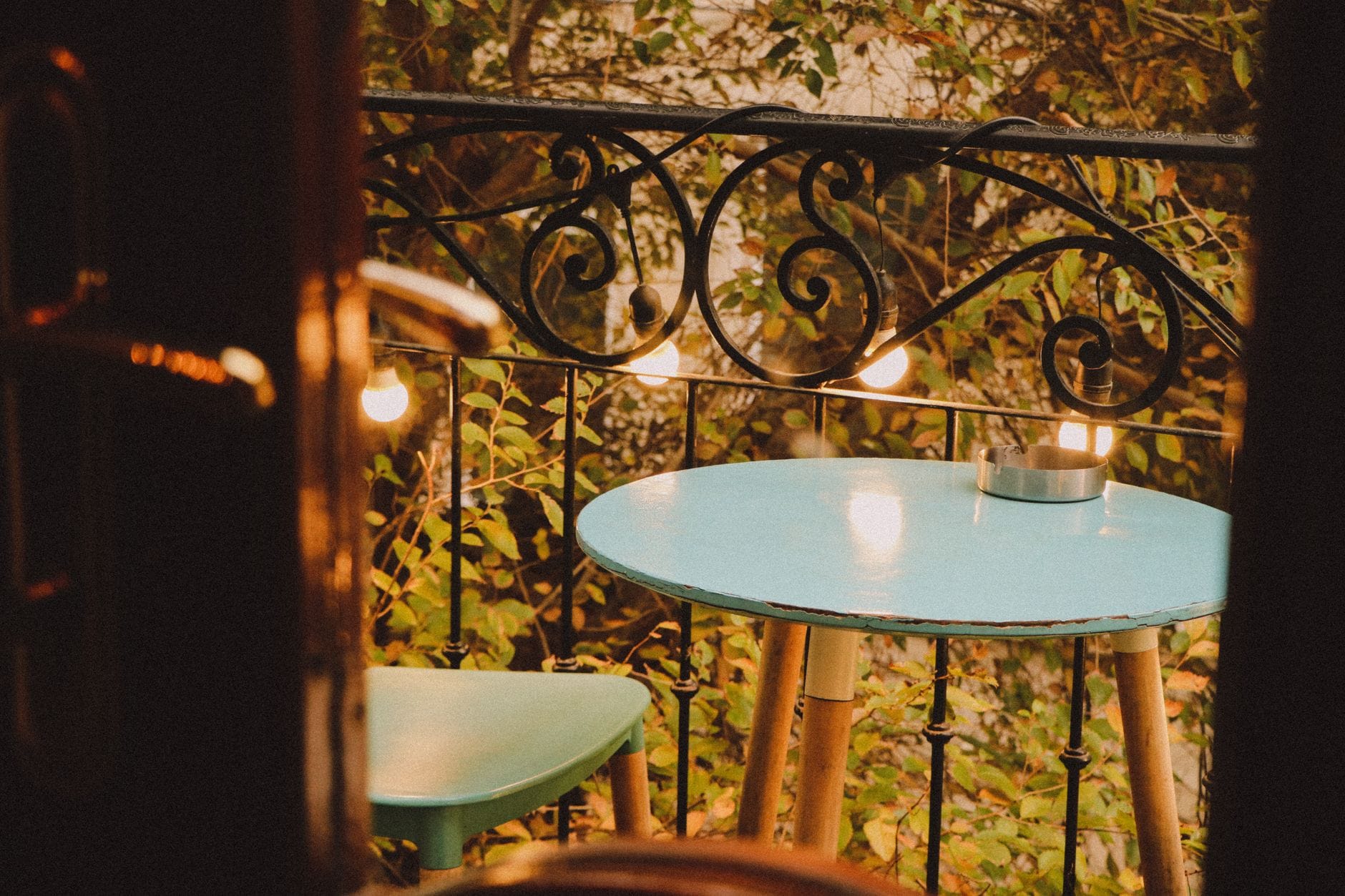 Jak urządzić wygodny i funkcjonalny balkon w bloku: praktyczny poradnik krok po kroku Przytulny mały balkon w bloku z niebieskim stolikiem, krzesłem i lampkami