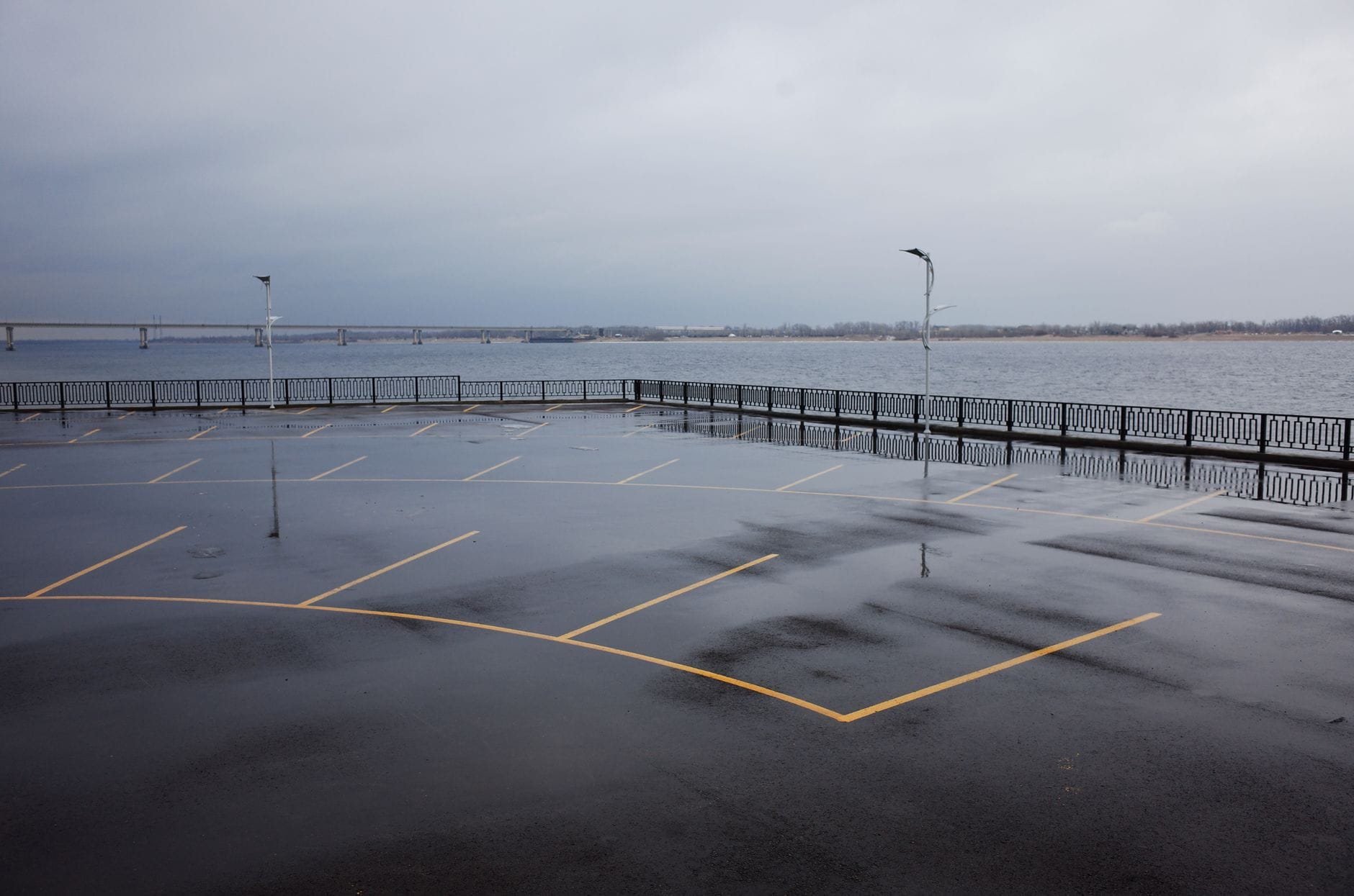 Opuszczony parking nad wodą z mokrym asfaltem i pochmurnym niebem